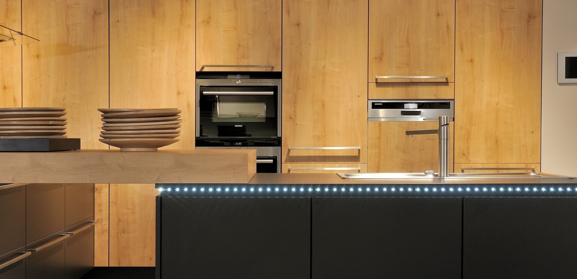 Die Kombination aus schwarzen Fronten und Echtholzfronten schafft in dieser Küche sowohl Wärme als auch Distanz.
