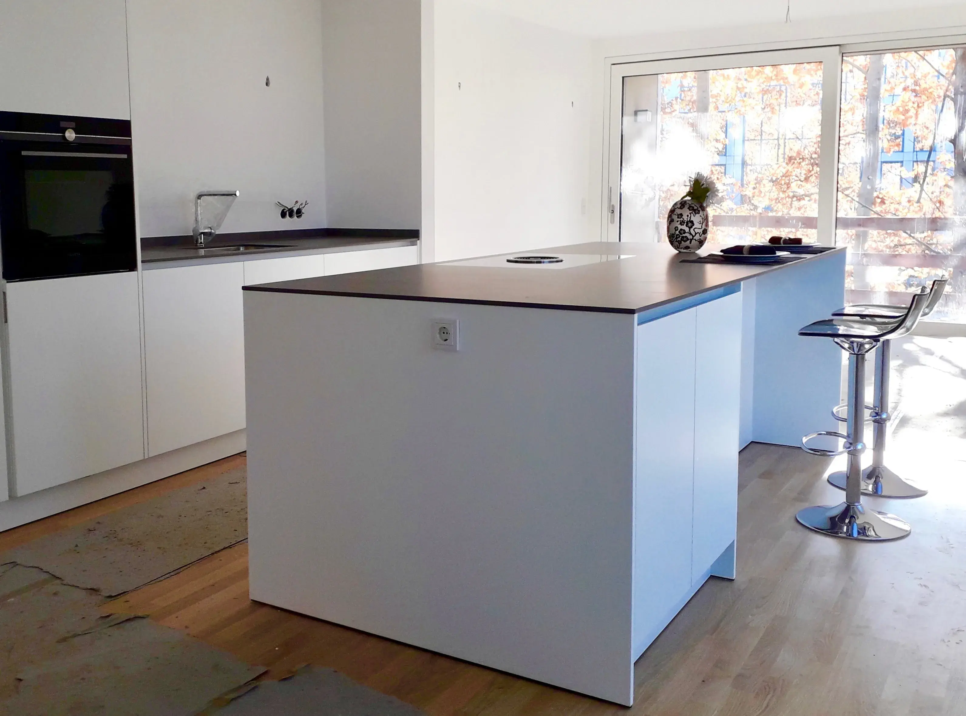 Moderne, helle Küche mit Kücheninsel und Barhockern, Sonnenlicht fällt herein.