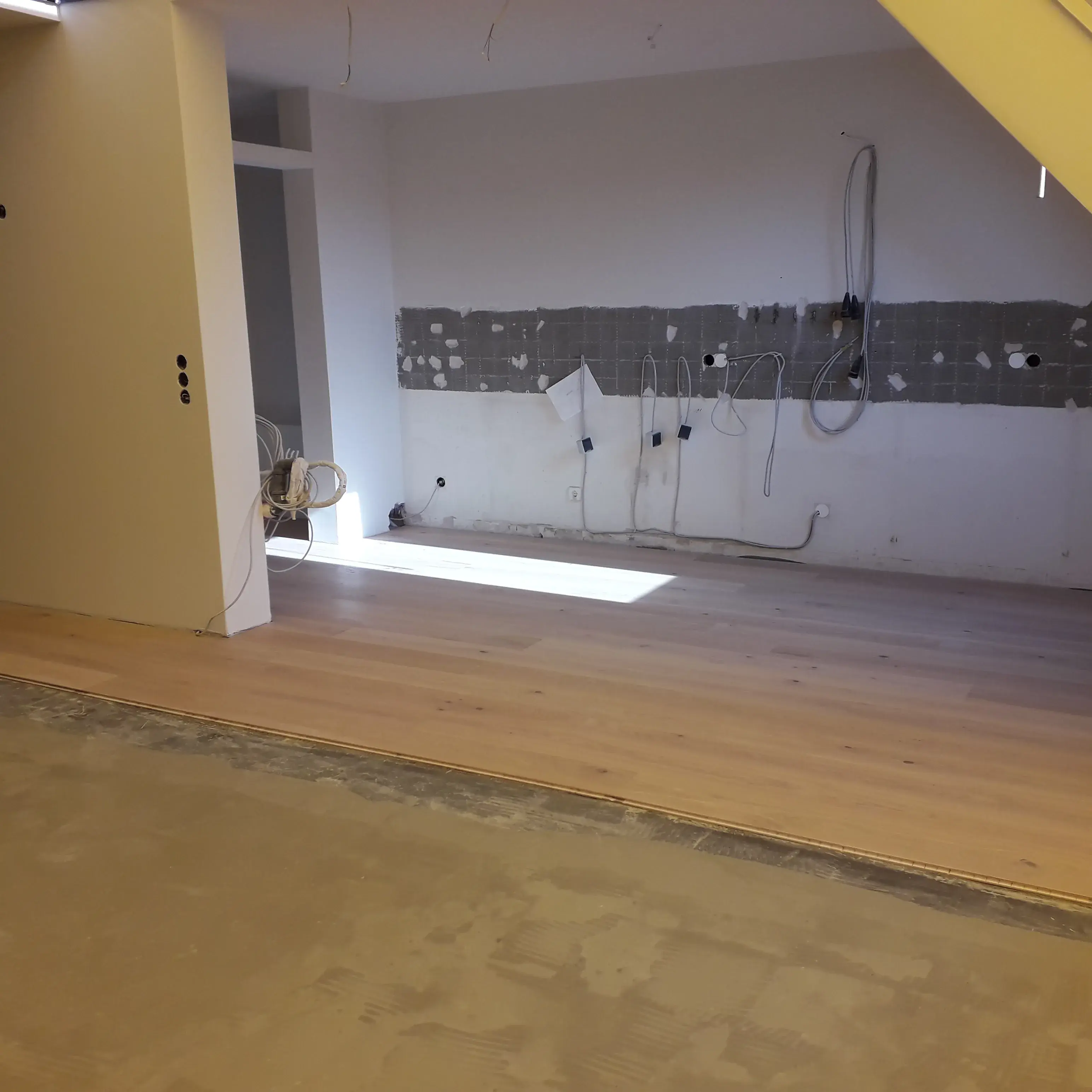 Renovierung einer Küche, teils mit neuem Holzboden, Wandinstallationen sichtbar