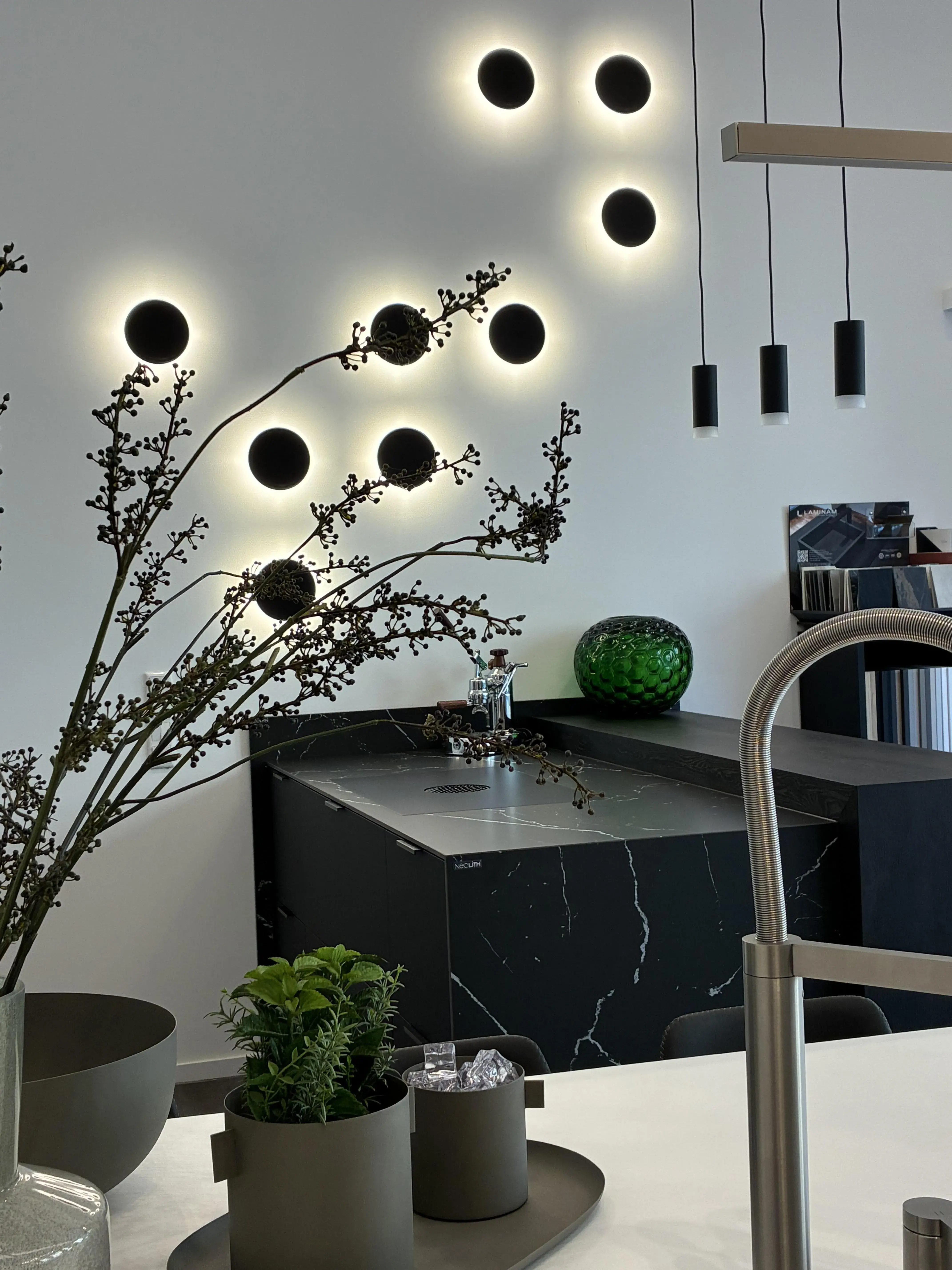 Moderne Küche mit Pflanzen, dunklem Marmor und runden Wandlichtern