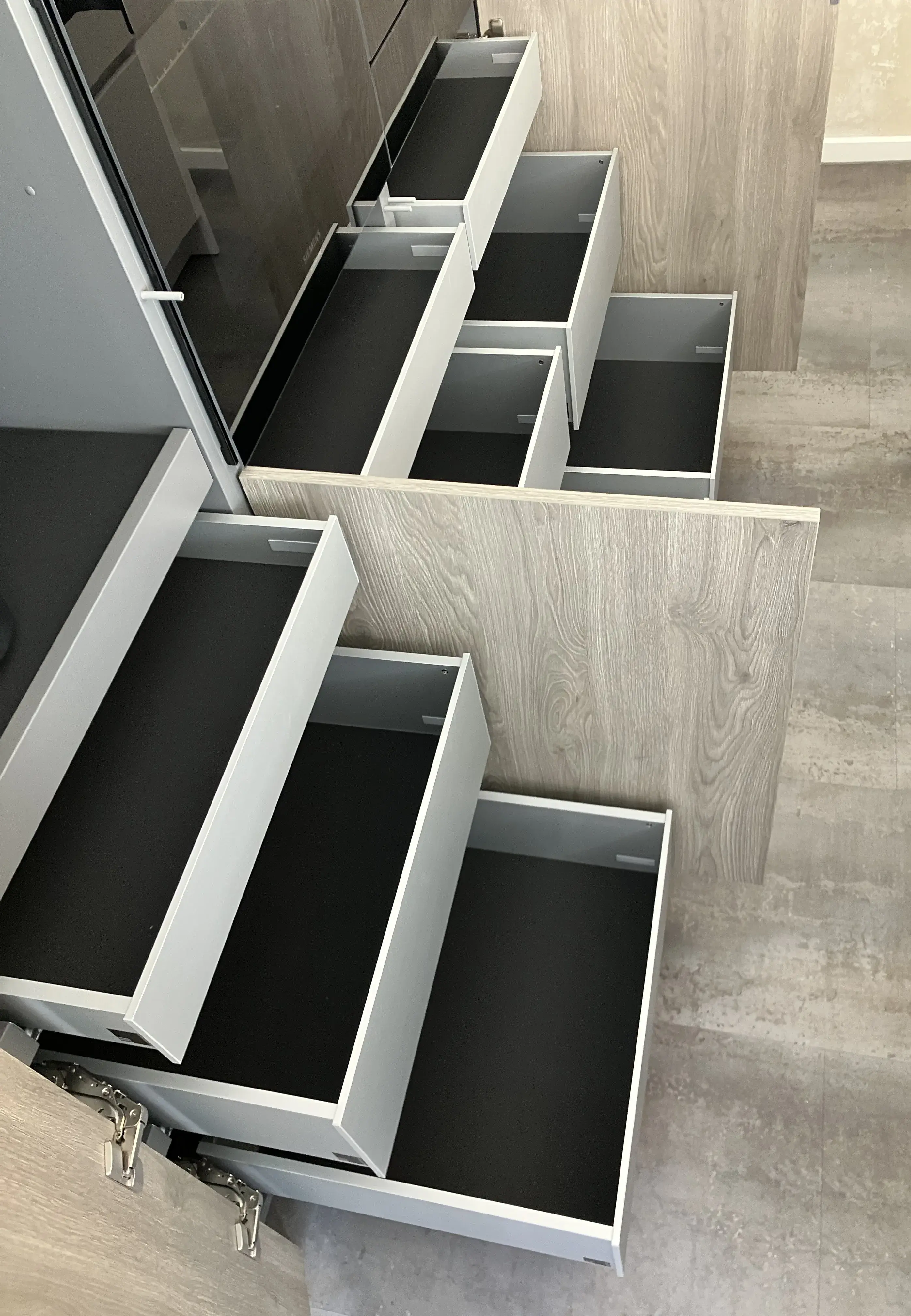 Mehrere geöffnete Schubladen in einem modernen Holzschrank, schwarz ausgekleidet.