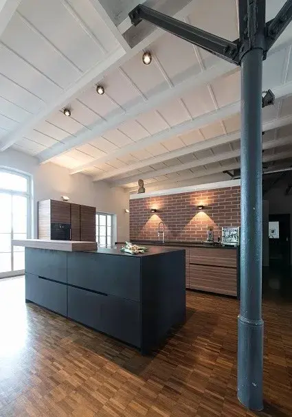 Moderne Küche mit Kochinsel, Backsteinwand und Holzfußboden in Loft-Atmosphäre.